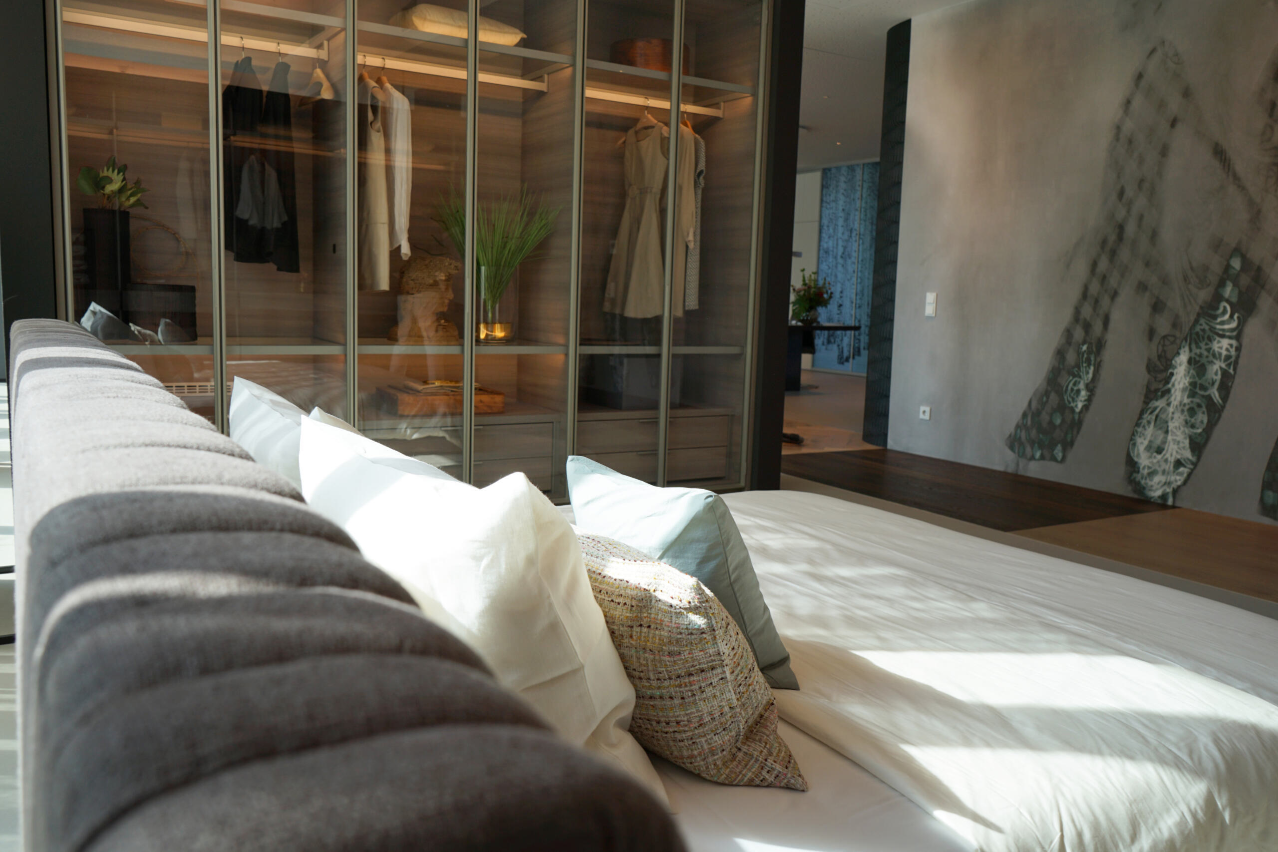 Im Schlafzimmer der Ausstellung bieten die luxuriösen Möbel die perfekte Ergänzung zum fugenlosen Boden. An der Wand ist ein auffälliges Motiv einer Vliestapet von Wall&Deco angebracht.