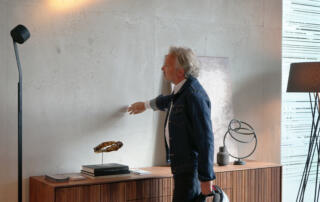 Unsere von Hand gespachtelte Betonoptikwand wird individuell auf die Wand angepasst. Die Loftoptik wird hier von einem Holz-Sideboard und schönen Standlampen optimal in Szene gesetzt.